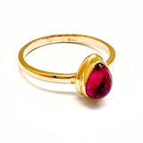 Turmaliini, kirkkaan vaaleanpunainen pisaranmuotoinen kivi kultaisessa sormuksessa